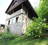 A cottage in Holčíkovce with a stone facade surrounded by greenery and flowers.