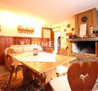 A cottage with a fireplace, a table, and a decorated wall. Dominated by wooden elements and a cozy atmosphere.