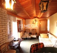 Living room in a cottage with a brick wall and wooden decor on the ceiling.