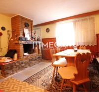 Interior of a cabin with a fireplace, wooden table and chairs, carpet with decorative pattern.