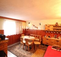 Interior of a cabin with wooden decor, a sofa, and a dining table with rustic chairs.