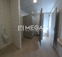 In the offices, there are toilets with white tiles and several stalls.