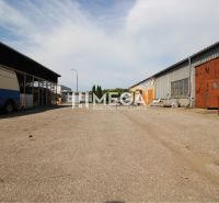The exterior of warehouses and halls on Fidlikova Street in Humenné with parked vehicles.