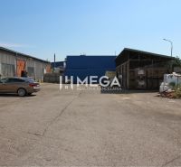 An area of warehouses and halls in Humenné on Fidlikova Street with a parked car.