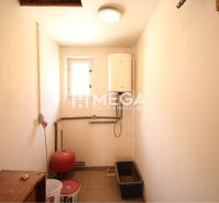 Small room with a boiler, electrical wiring, and a window, interior of an office.