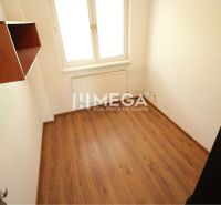 Small office with a shelf, wooden-patterned floor, window, and radiator.