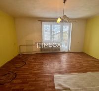 A room in a family house with a wooden decor floor and a yellow wall.