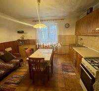 A kitchen in a family house with wooden decor on the chairs and a large table.