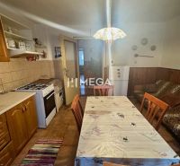 A kitchen in a family house with wooden decor, a dining table, a stove, and a refrigerator.