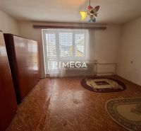 Interior of a family house with possibly an older carpet, wardrobes, and a window with a curtain.