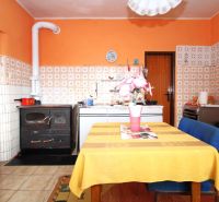 A kitchen in a family house with orange walls, tiles, and a dining table.