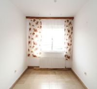 A room in a family house with a window, floral curtains, and tiles.