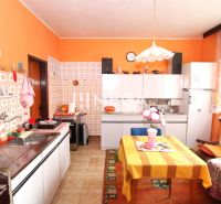 A kitchen in a family house with a colorful wall, tiled cladding, and a dining table.
