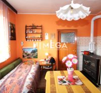 A kitchen in a family house with orange walls, a stove, and a floral decoration on the table.