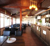 Interior of dining spaces with wooden elements, black chairs, and decorative lights.