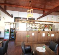 Gastro premises with a wooden bar and ceiling, floor with wooden decor, flowers on the tables.