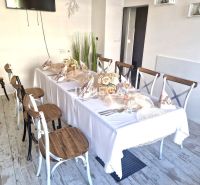 A table set with decorations, a floor with wooden decor, chairs in dining spaces.