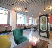 The interior of a café with wooden decor on the floor, comfortable armchairs, and decorations on the ceiling.