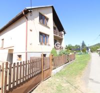 A family house in Nižné Ladičkovce with a garden, wooden fence, and asphalt road.