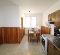 A kitchen in a family house with wooden paneling and a dining table.