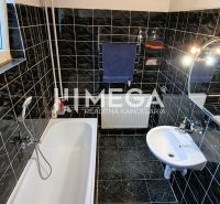 A bathroom in a family house with black tiles, a bathtub, and a mirror.