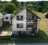 A family house in Nižné Ladičkovce, with a wooden fence and lawn, surrounded by greenery.