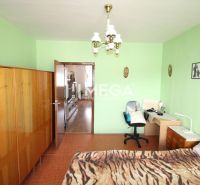 A room with green walls, a wooden wardrobe, and a desk in a four-room apartment.
