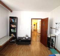 A room in a 4-room apartment with a bookshelf and a floor with a wooden decor.