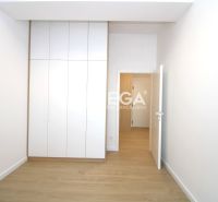 A room in a three-room apartment with a white built-in wardrobe and a floor with a wooden decor.