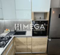 A kitchen with white cabinets, gray tiles, and appliances in a 3-room apartment.