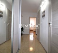 A hallway with ceramic tiles in a 3-room apartment with white walls and light-colored doors.