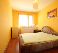 A bright bedroom with yellow walls and a wood-patterned floor in a 4-room apartment.