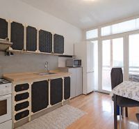 A kitchen in a 3-room apartment with a wooden decor floor and a dining area.