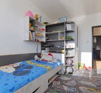 A children's room in a 3-room apartment with a bed and shelves full of toys and books.