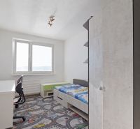 Children's room in a 3-room apartment with a bed and a desk on a colorful carpet.