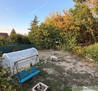 A garden by the cottage in Nové Zámky with a swing and a greenhouse surrounded by greenery.