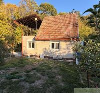 A cottage in Nové Zámky, surrounded by greenery, with a red roof in a natural setting.