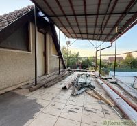The terrace of the cottage in Nové Zámky with clutter and building materials, a peaceful garden in the background.