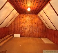 Attic room in a cabin with wooden paneling and flooring.