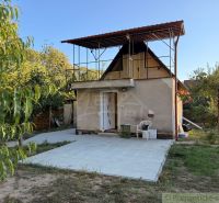 A cottage in Nové Zámky surrounded by greenery with an outdoor terrace on a paved area.