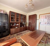 Living room in a family house with cabinets, a table, and a patterned carpet.