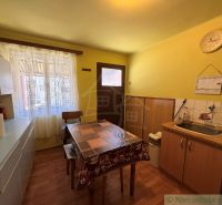 A kitchen in a family house with a wood-patterned floor and yellow walls.