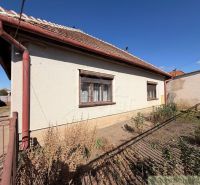 A family house in Hurbanovo with a white facade, brown shutters, and a garden behind the house.