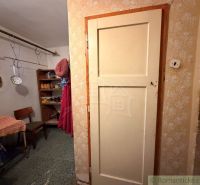 Interior of a family house with a hallway, a chair, and shelves. Kitchen tools are hanging here.