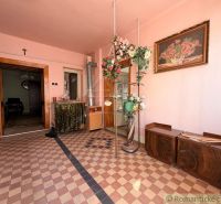 The interior of a family house with pink walls, floral decorations, and a checkered floor.