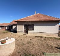 A family house in Hurbanovo with a sloped roof, a well, and sparse grass around.