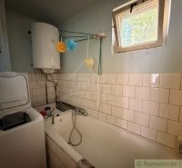 Bathroom in a family house with a bathtub, boiler, and washing machine.