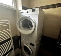 Bathroom in a 2-room apartment with a washing machine and dryer stacked on top of each other.