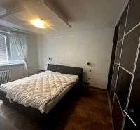 Bedroom in a two-room apartment with a bed, wardrobe, and wooden decor flooring.