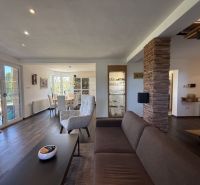 Living room with wood-patterned flooring and a dining area in a family house.